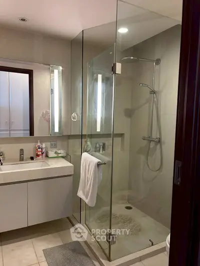 Modern bathroom with glass shower enclosure and sleek vanity in a contemporary home.
