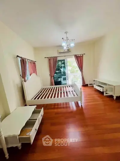 Spacious bedroom with elegant wooden flooring and large windows for natural light.