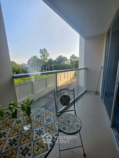 Charming balcony with decorative table set and lush green view, perfect for relaxation.