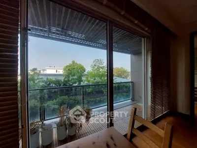 Spacious balcony with lush green view and wooden flooring, perfect for relaxation.