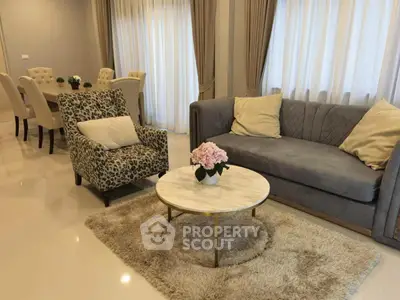 Elegant living room with plush sofa, stylish armchair, and dining area in modern home.