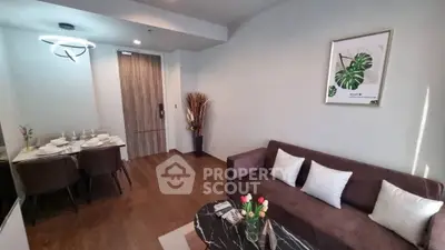 Modern living room with stylish decor and dining area, featuring elegant lighting and wooden flooring.