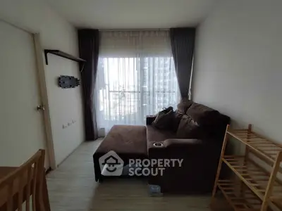 Cozy living room with brown sofa and large window offering city view