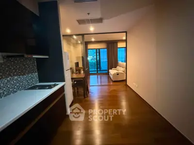 Spacious open-layout living room with wooden flooring and modern kitchen area.