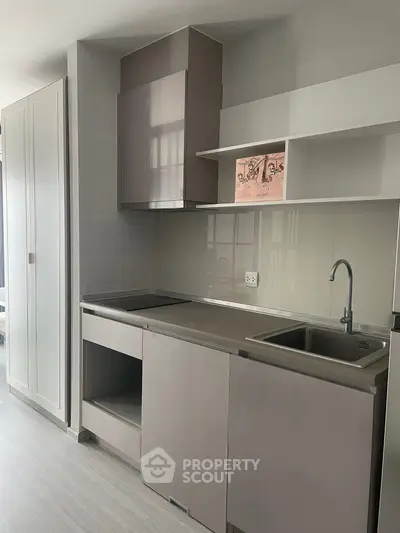 Modern kitchen with sleek cabinetry and stainless steel sink in a stylish apartment.