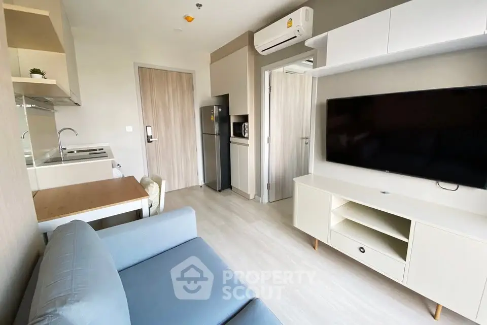 Modern living room with sleek furniture and integrated kitchen in compact apartment.
