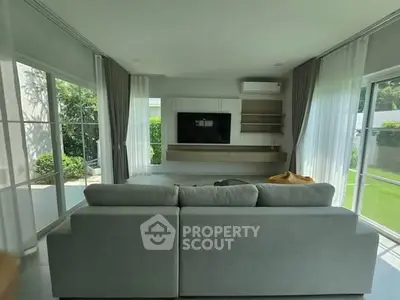 Spacious living room with modern decor and large windows overlooking a lush garden.