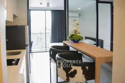 Modern apartment interior with stylish kitchen and dining area, featuring a balcony view.