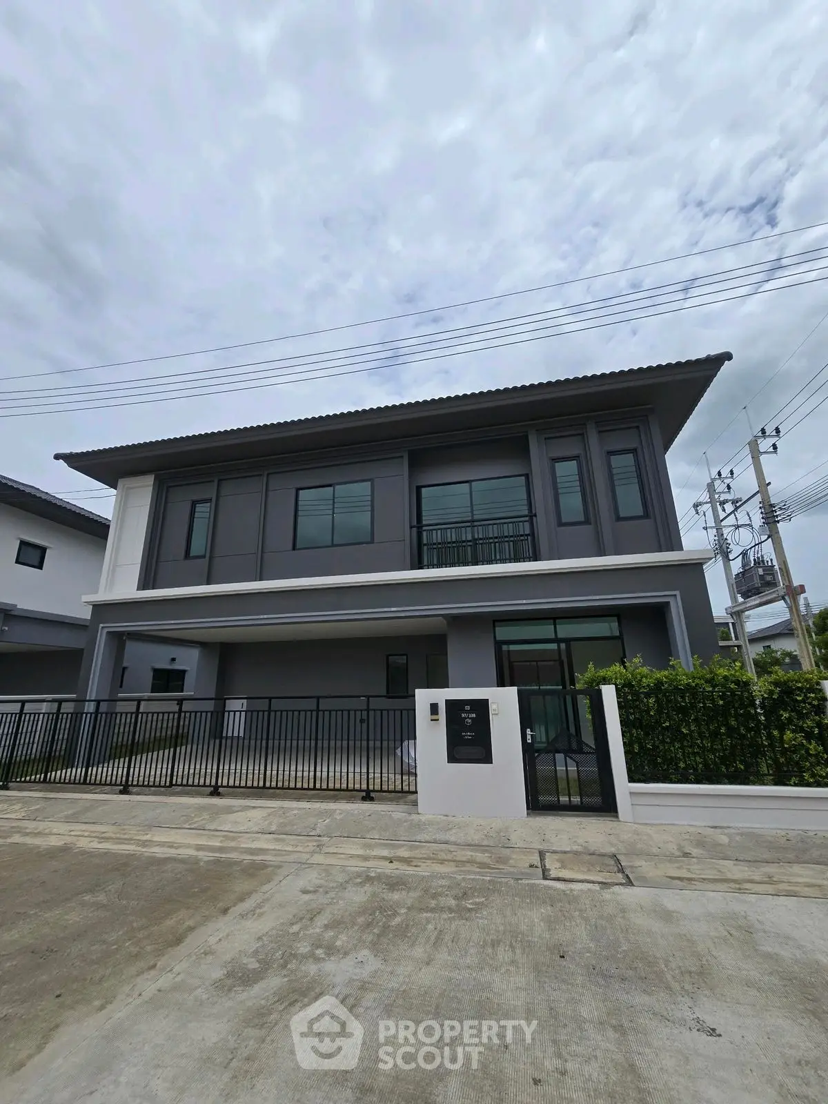 Modern two-story house with sleek design and spacious driveway in suburban neighborhood.