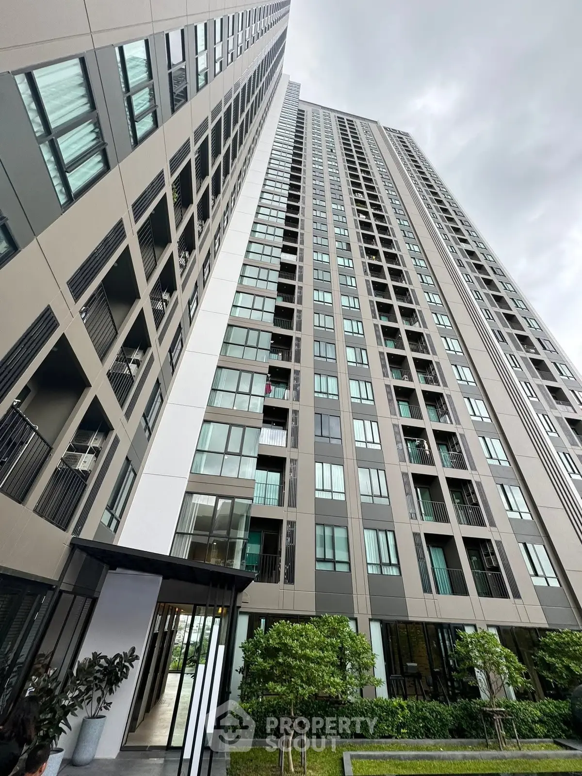 Modern high-rise residential building with sleek architecture and lush greenery