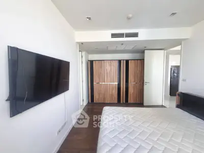 Spacious bedroom with modern design and wall-mounted TV in a stylish apartment.
