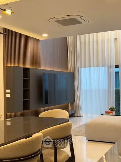 Modern living room with sleek design, large TV, and elegant dining area.