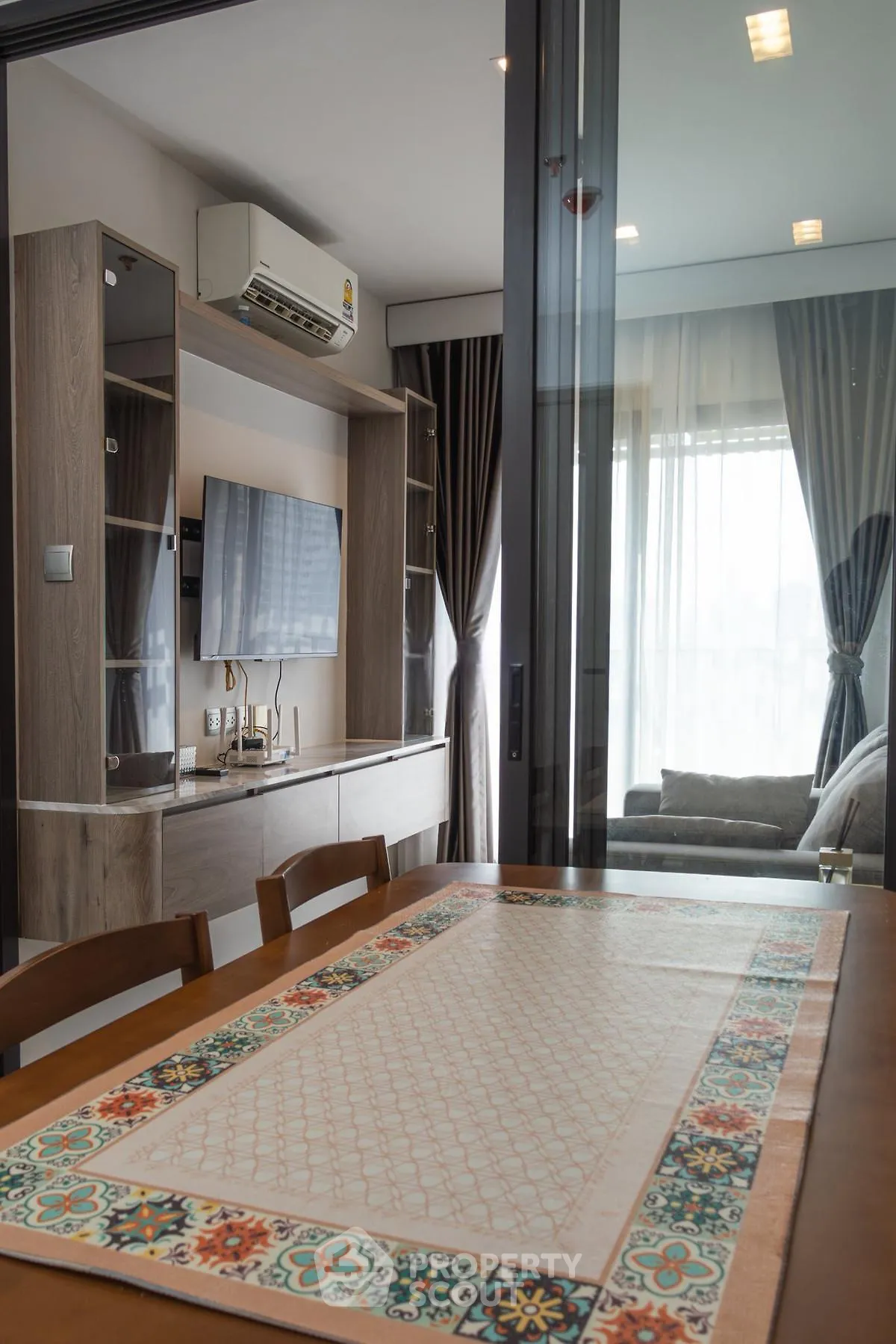 Modern living room with stylish decor and air conditioning, featuring a cozy dining area and elegant curtains.