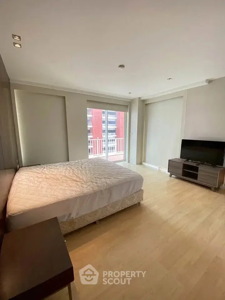 Spacious bedroom with modern decor and balcony access in urban apartment