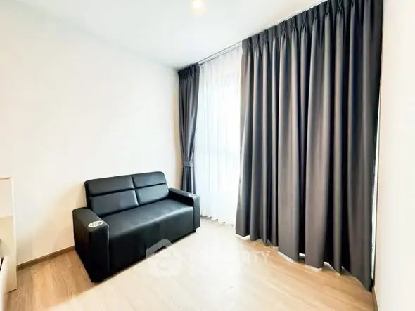Modern living room with sleek black sofa and floor-to-ceiling curtains