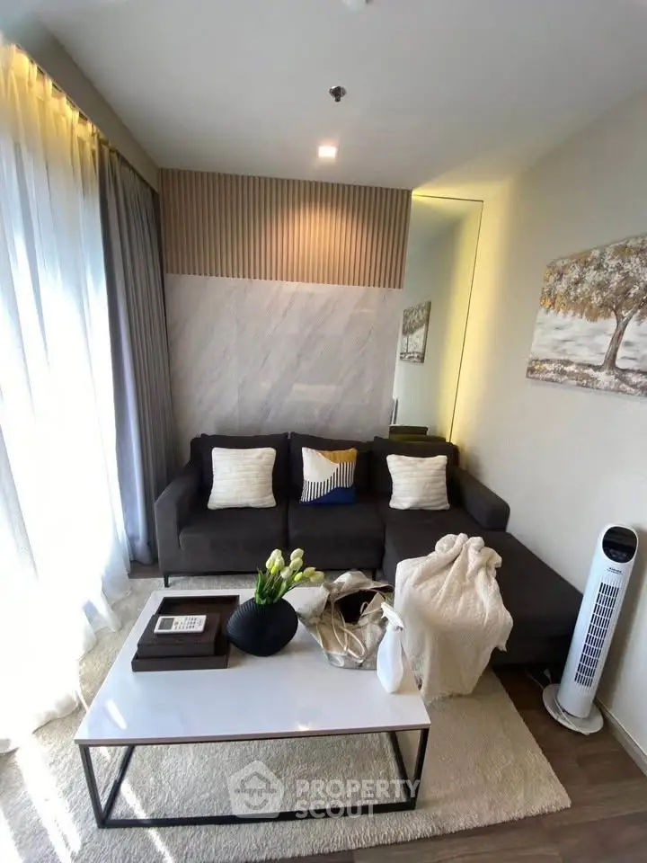 Modern living room with stylish decor, cozy sofa, and natural light from large windows.