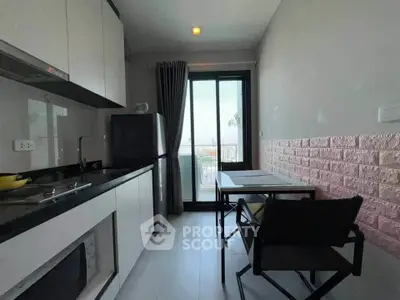 Modern kitchen with sleek design and balcony view, featuring compact dining area and appliances.