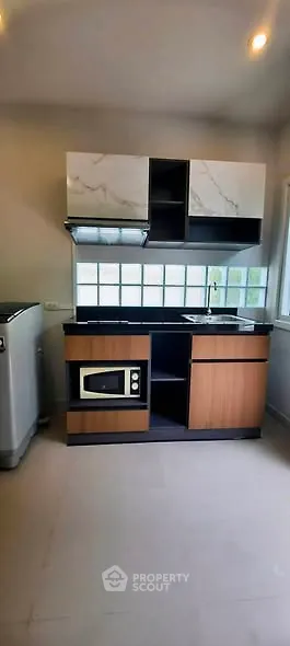 Modern kitchen with sleek cabinetry and built-in microwave, featuring a large window for natural light.