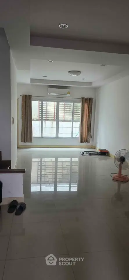 Spacious unfurnished living room with large window and glossy tiled floor