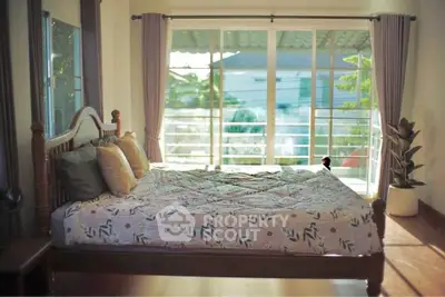 Spacious bedroom with large windows and balcony access, featuring elegant wooden bed and modern decor.