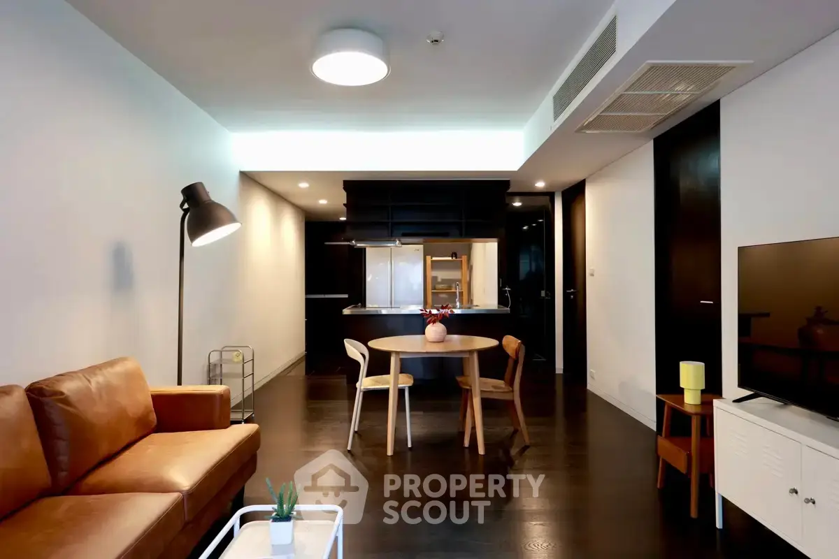 Modern living room with open kitchen, stylish furniture, and ambient lighting.