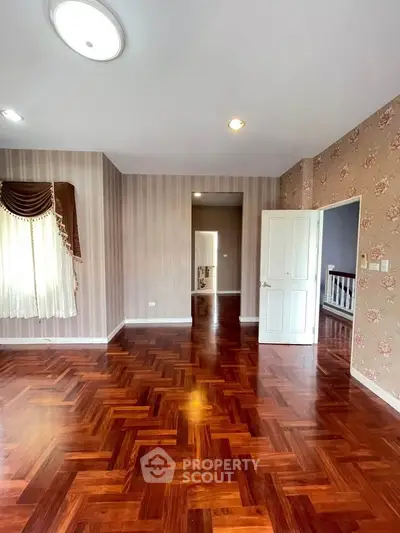 Spacious room with elegant parquet flooring and stylish wallpaper, perfect for a cozy living space.