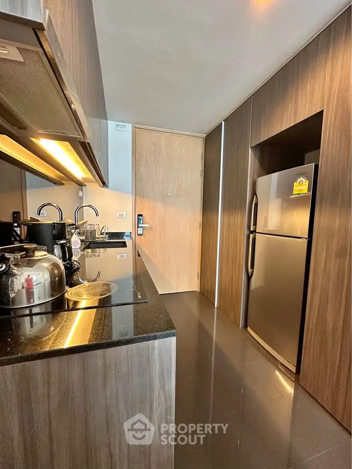 Modern kitchen with sleek appliances and wood cabinetry, featuring a stainless steel fridge and electric stove.