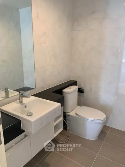 Modern bathroom with sleek fixtures and large mirror in a stylish real estate property.