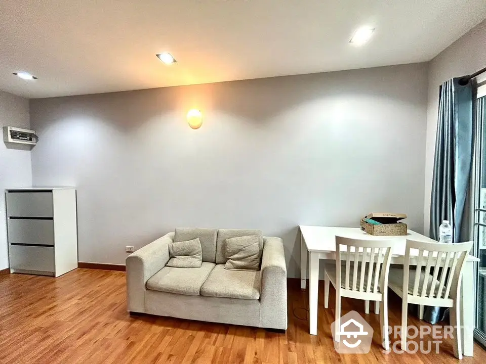 Modern living room with cozy sofa and dining area, featuring wooden flooring and ambient lighting.