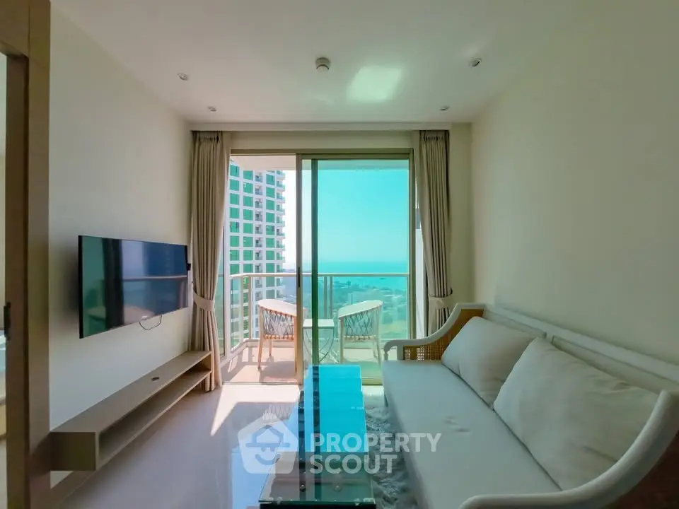 Modern living room with ocean view and balcony access in a high-rise apartment.