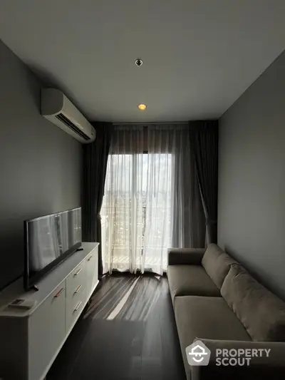 Cozy living room with modern sofa and TV, featuring floor-to-ceiling windows and elegant curtains.