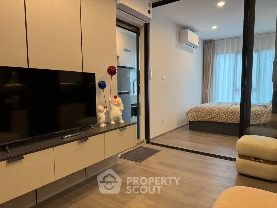 Modern living room with open layout leading to a cozy bedroom, featuring stylish decor and natural light.