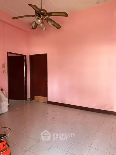 Spacious room with pink walls and ceiling fan, ideal for customization.