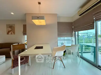 Modern living room with stylish dining area and large windows offering natural light.