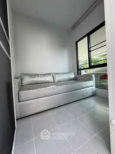 Cozy small room with modern sofa and large window offering natural light.