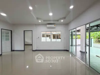 Spacious modern living room with large windows and glossy tiled floors, perfect for natural light and open living.