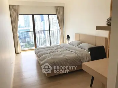 Spacious bedroom with city view and modern furnishings in high-rise apartment.