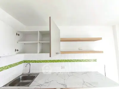 Modern kitchen with marble countertop and open shelving, featuring a sleek sink and green tile accents.