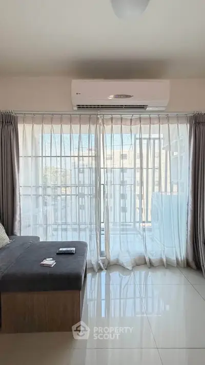 Bright living room with large windows and air conditioning, featuring modern decor and city view.