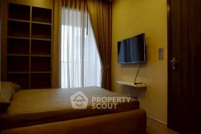 Cozy bedroom with modern TV setup and elegant curtains, perfect for relaxation.