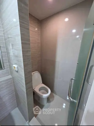 Modern bathroom with sleek tile design and glass door enclosure.