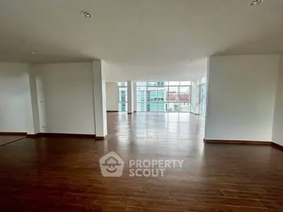 Spacious open-plan living area with hardwood floors and large windows offering abundant natural light.