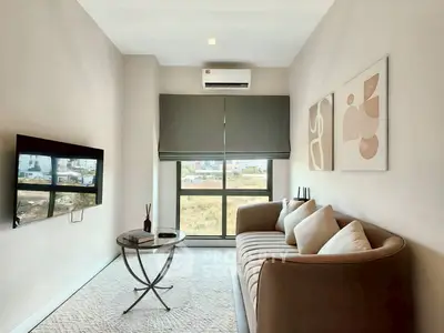 Modern living room with stylish sofa, wall art, and large window offering natural light.