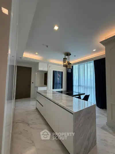 Luxurious modern kitchen with marble island and elegant lighting in high-end apartment.