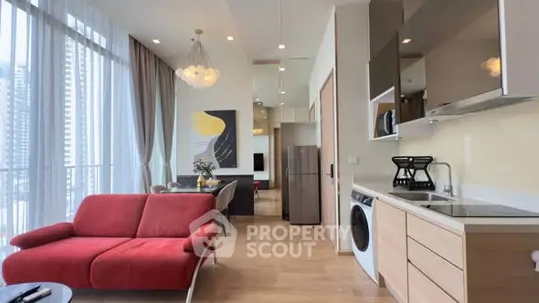 Modern open-plan living room with red sofa, dining area, and sleek kitchen appliances.