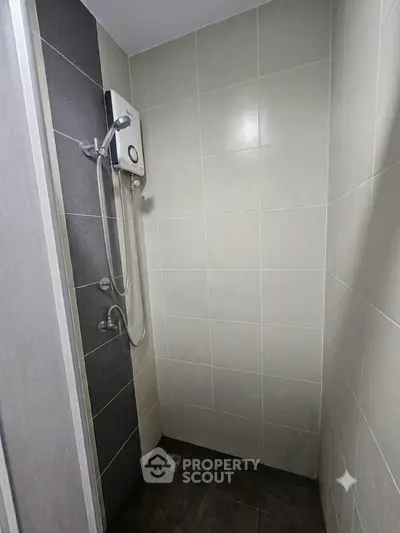 Modern bathroom shower area with sleek tiles and electric water heater.