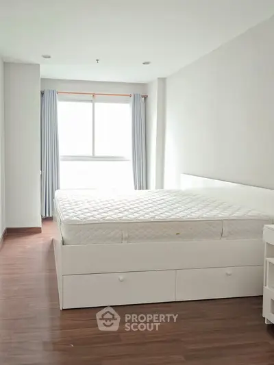 Bright and spacious bedroom with large window and wooden flooring