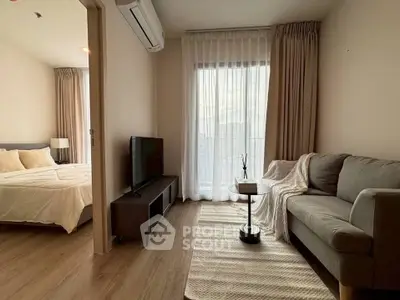 Modern living room with cozy sofa and TV, adjacent to a stylish bedroom.