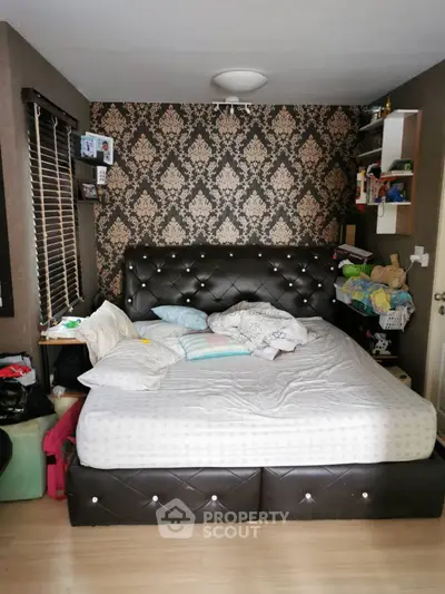 Cozy bedroom with elegant wallpaper and plush bed, perfect for relaxation.