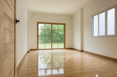Spacious empty room with large windows and wooden flooring, perfect for customization.